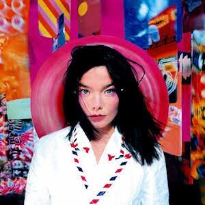 Capa do álbum post da cantora Bjork. Na imagem uma foto da cantora vestindo uma espécie de blazer branco, com detalhes nas barras da lapela de lista em azul, vermelho e preto. A cantora que tem cabelos pretos lisos abaixo do ombro, olha para frente. Atrás da cabeça a uma forma de aparência plástica em rosa chock escuro. O fundo da foto tem o que  parecem ser telas pintadas sem moldura, dispostas semi lateralmente e com imagens de diversas formas e em tons vibrantes 