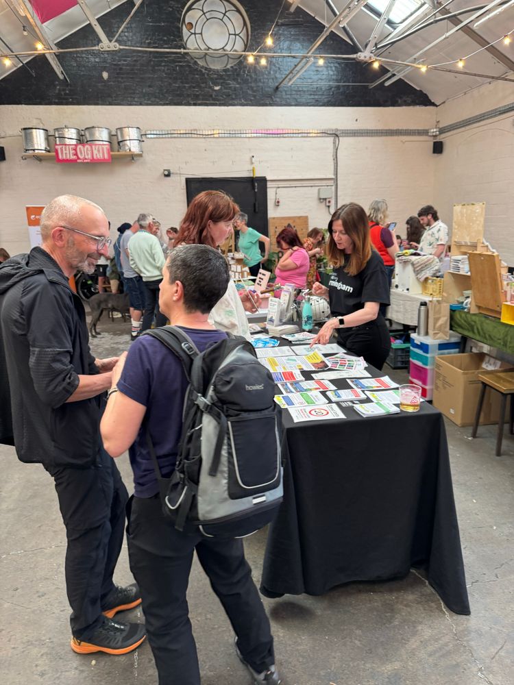 Some people are deep in conversation next to a table covered in leaflets 