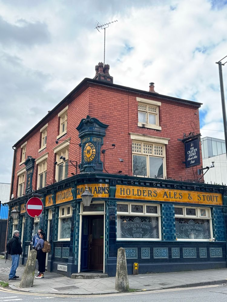A traditional Victorian pub with tiled and red brick walls on a street corner . 