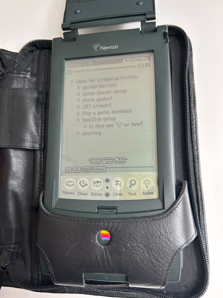 the messagepad 120 in its case with the cover up. oh my!! looks like someone left a bullet list open. what does it say..?

""ideas for stream activities""
-garden harvest
-sheep shaver setup
-photo gacha?
-CRT stream?
-play a game, dumbass
-Basillisk setup
     - is that one "L" or two??
-chatting