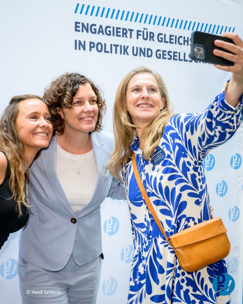 Auf dem Foto sieht man nebeneinander Christina Wolff, Judith Rahner und Alexandra Kühnen, die ein Selfie vor einer Fotowand des Deutschen Frauenrats machen.