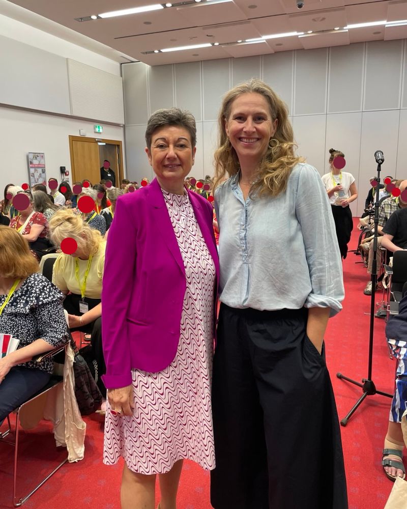 Man sieht Sylvia Bühler (ver.di-Bundesvorständin) und Alexandra Kühnen (bukof-Vorständin) in einem Saal stehen. Links und rechts sind Stuhlreihen aufgebaut mir Zuschauer*innen der Veranstaltung