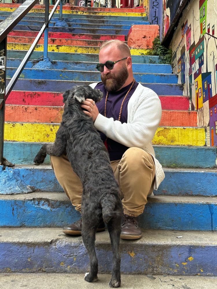 Bearded homosexual on rainbow steps, petting a most angelic baby dog