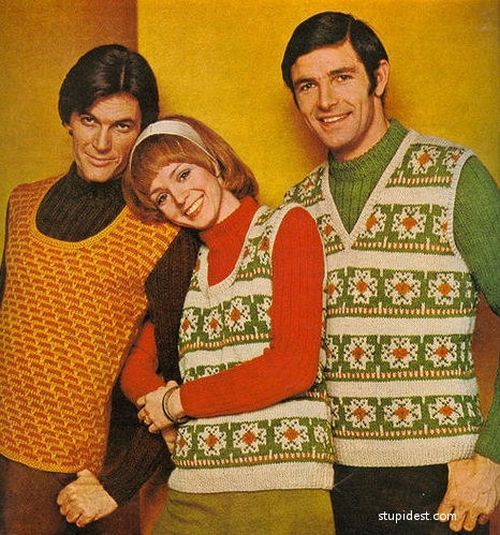 Photo from the '70s of three important style influencers. On the left is a man with dark hair rocking an orange vest over a brown turtleneck. The redheaded woman in the middle is sporting a decorative vest with snowflakes over a red turtleneck. The man on the far right is wearing a vest of the same design as the woman, but he's mixing it up with a green turtleneck. 

Words cannot accurately describe the style that is just dripping from this image.