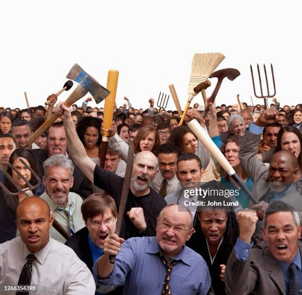 a stock image of an angry mob of people facing the camera with angry expressions, many are wielding pitchforks, axes, baseball bats, etc