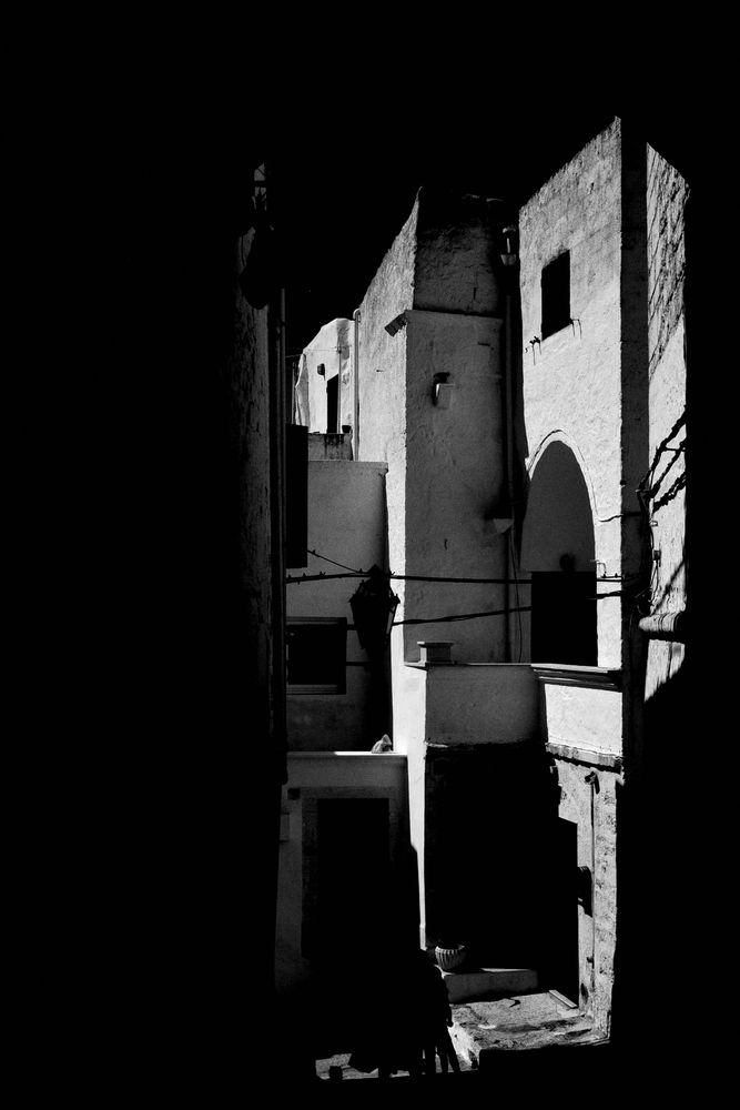Schwarz-weiß Foto eines Hinterhof in ostuni. Dramatische Kontraste, Rundbogen, offene Treppen, Balustraden