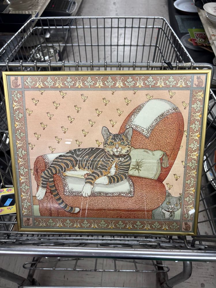 Art in a brass frame - cat lounging on a red chair with duck wallpaper behind it. 