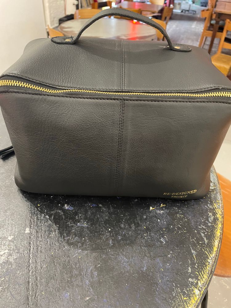A rectangular black leather bag with a handle from re: designed project 
