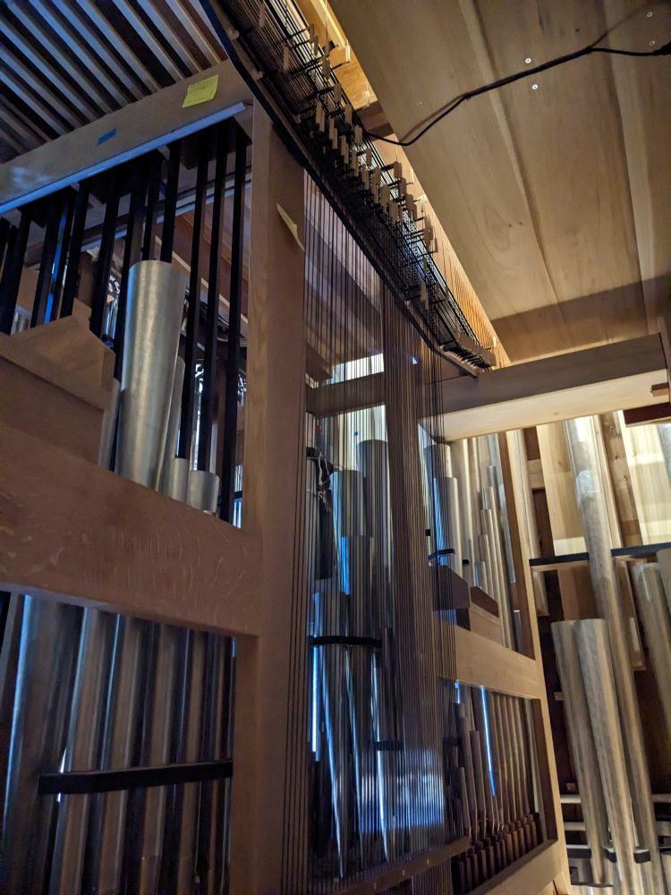 Inside of pipe organ, showing wood framing, metal pipes, and carbon fiber/steel action connections 