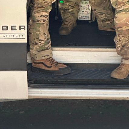 Zoomed in image of a van full of a heavily-armed tactical team in multicam fatigues and masks. The agent on the leftnby the edge of the van door is wearing Vans Sk8-hi boots.