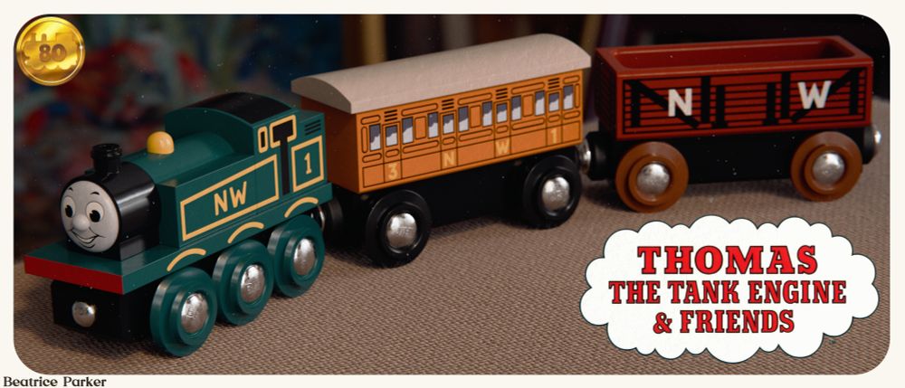 A 3D rendered scene of a wooden BRIO toy Thomas, with an orange coach, and red wagon. Thomas is in a faded blue-green colour, and has "NW" on his sides in yellow, along with his famous number 1.