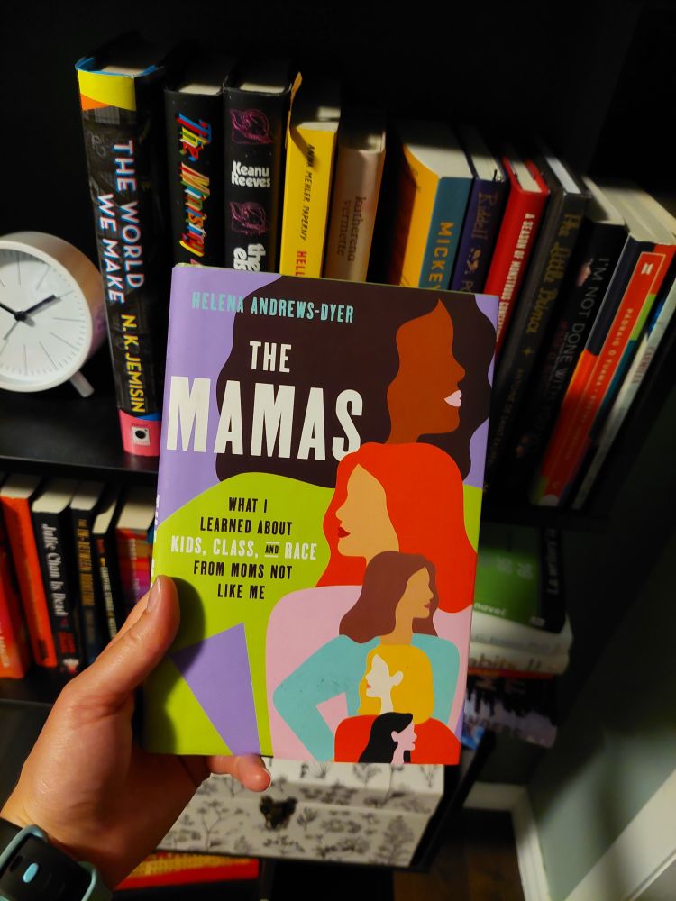 Picture of The Mamas by Helena Andrews-Dyer, held in front of a bookshelf. 