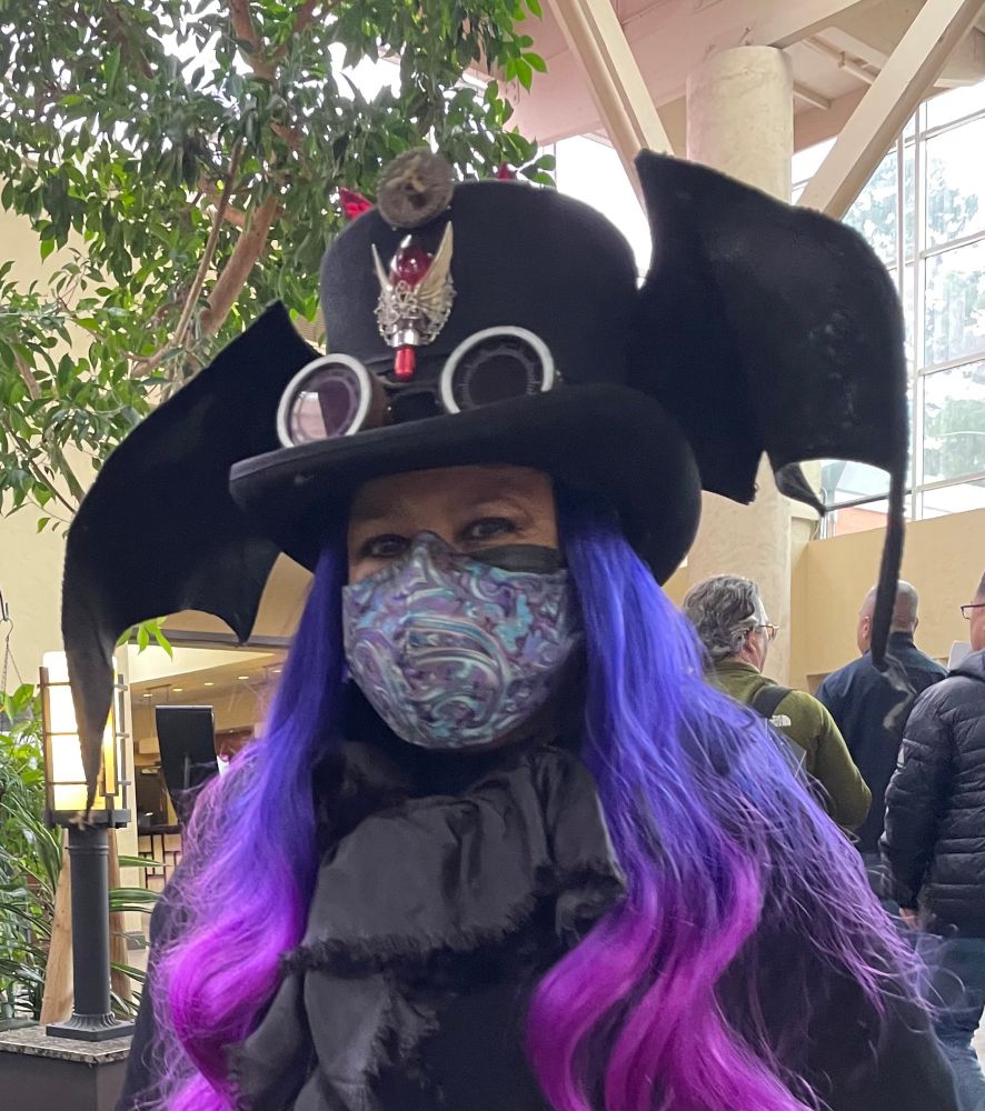 Morella aka my evil twin @JuaSaysHi in black winged top hat, giggles, purple & pink hair