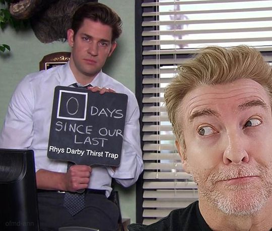 a meme from the office. A blackboard is being heldup that says '0 days since our last rhys darby thirst trap' rhys is looking on in the foreground.  HE KNOWS WHAT HE DOES