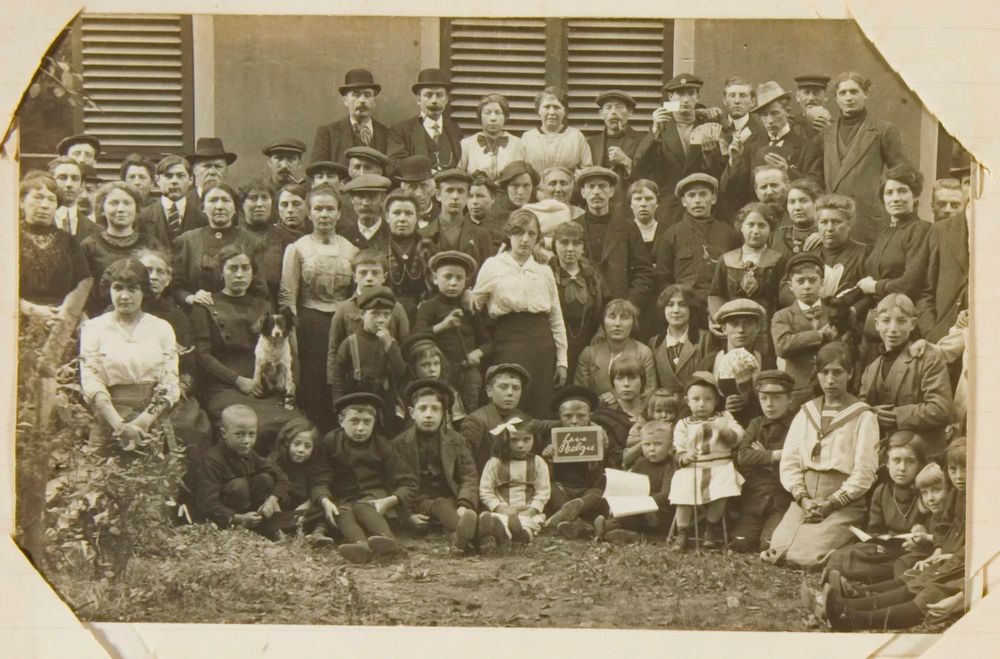 Groepsfoto van Belgische vluchtelingen in Arnhem in 1914. De groep bestaat uit hele gezinnen: vrouwen, mannen en kleine kinderen. Sommige mensen hebben hun huisdier mee. Een klein jongetje heeft een krijtbord vast met daarop de tekst "Leve België". Bron: Gelders Archief, fotograaf onbekend, toegang 1523 - 333-0004