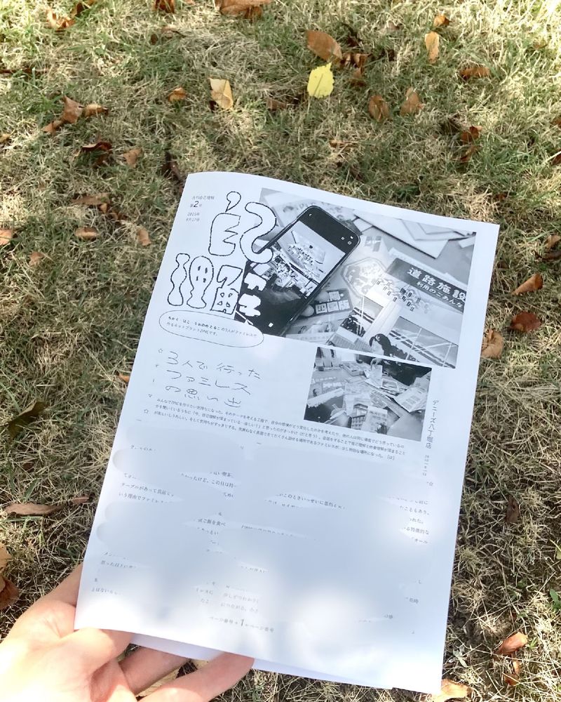 『月刊自己理解』第2号の写真。背景に芝生があり、左手で紙を持っている様子。
