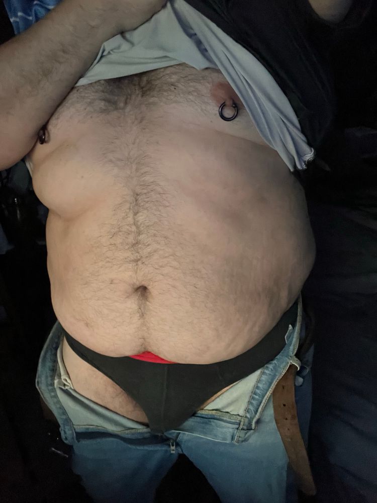 Me, a man, standing with my jeans undone and my shirt pulled off showing off my stomach and bulge