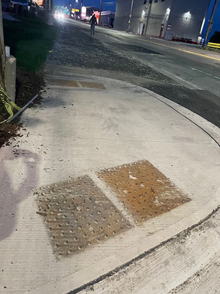 An approximately 2m length of sidewalk with curb cuts and tactile paving on opposite sides sits along the Bedford Highway. In one direction, the curb cut leads to a sloped gravel shoulder along the Bedford Highway instead of the sidewalk continuing.