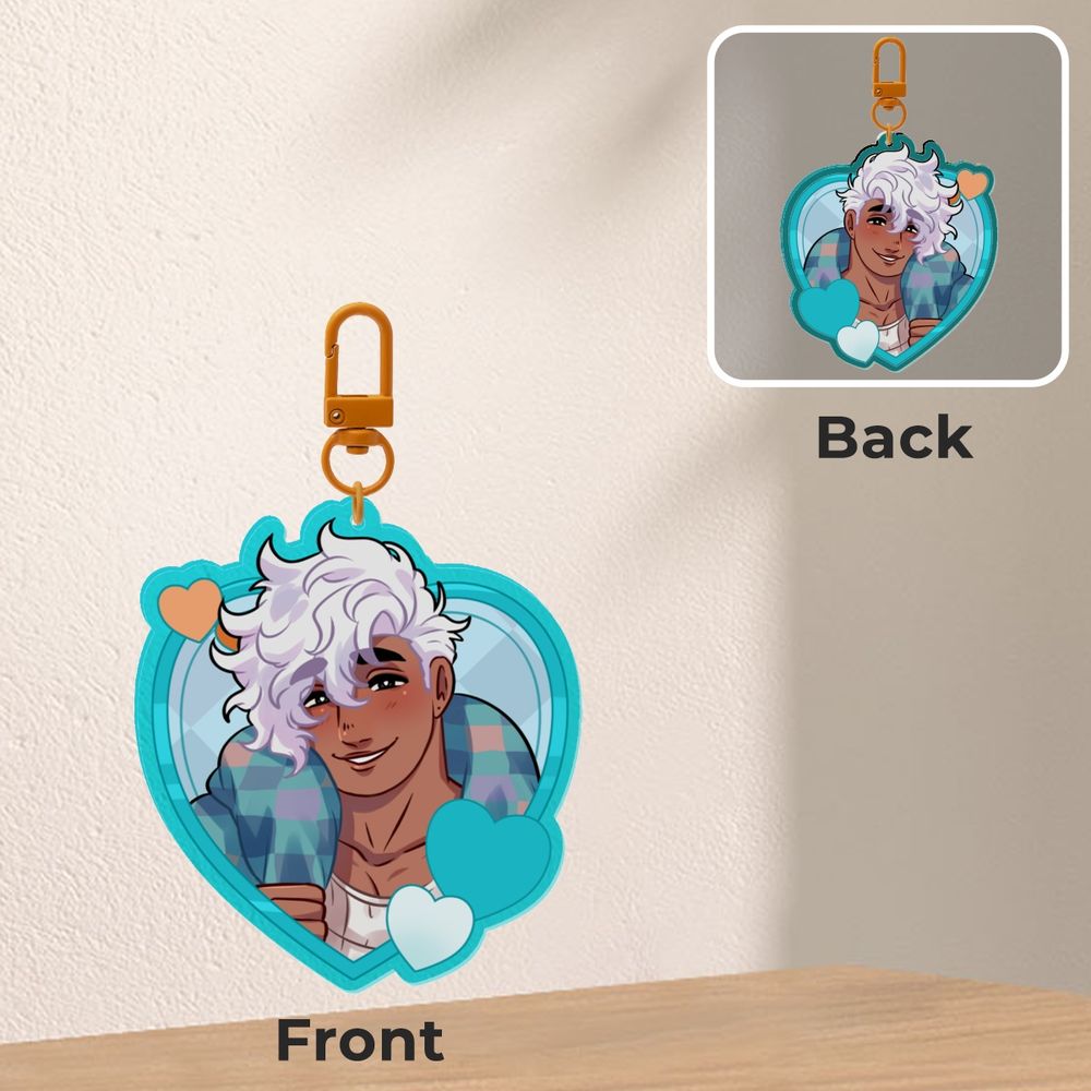 A heart-shaped charm of Mateo Manta.  The charm is turquoise and has a smiling Mateo on the front and back of the charm. 