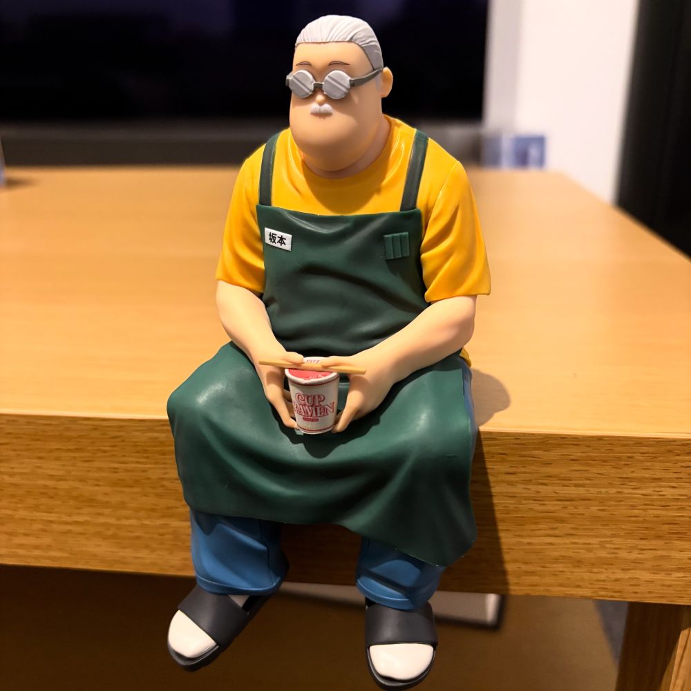 A Taro Sakamoto noodle stopper figure, Sakamoto-san is sat holding a cup ramen. 