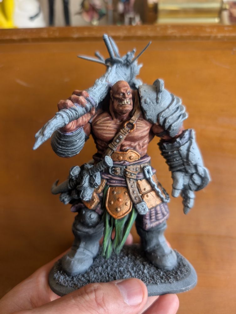 A game miniature of an orc-like monster, partially painted 