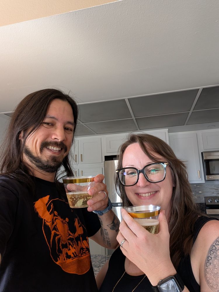 Two people holding glasses of champagne in a kitchen 