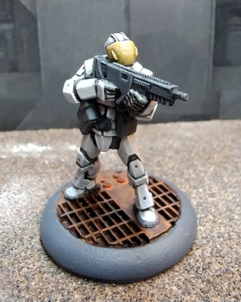 Three quarter view of a painted 28mm science fiction figure aiming a weapon