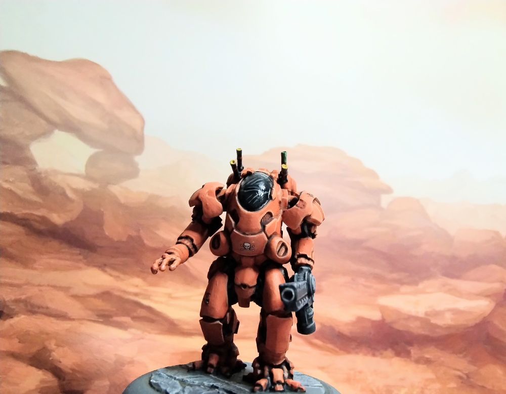 Miniature of a sci-fi armoured suit,
 painted orange in front of a background pictue of orange rocks