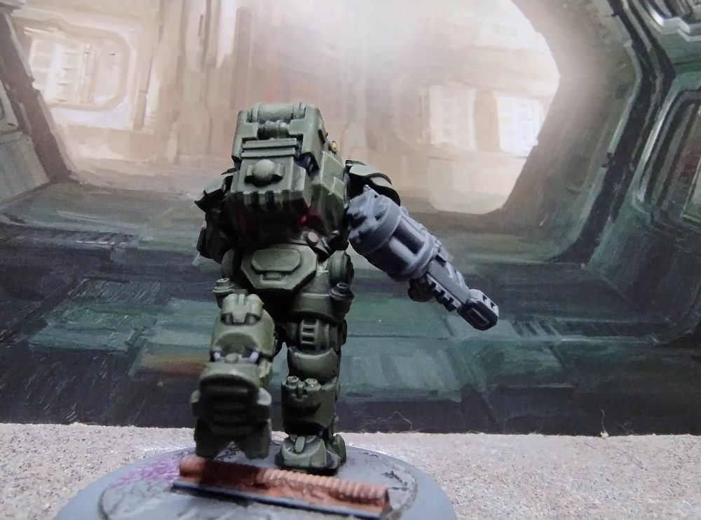 28mm Science fiction figure in heavy armour running away from the camera. The faint glow of position light visible beneath the backpack