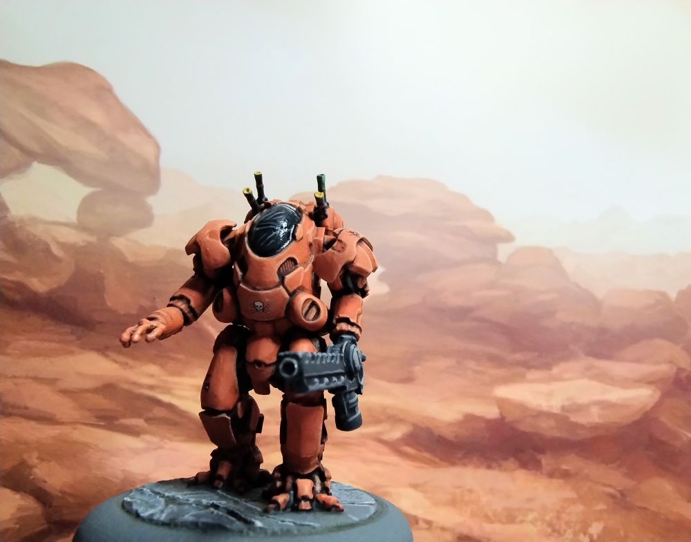 Miniature of a sci-fi armoured suit,
 painted orange in front of a background pictue of orange rocks