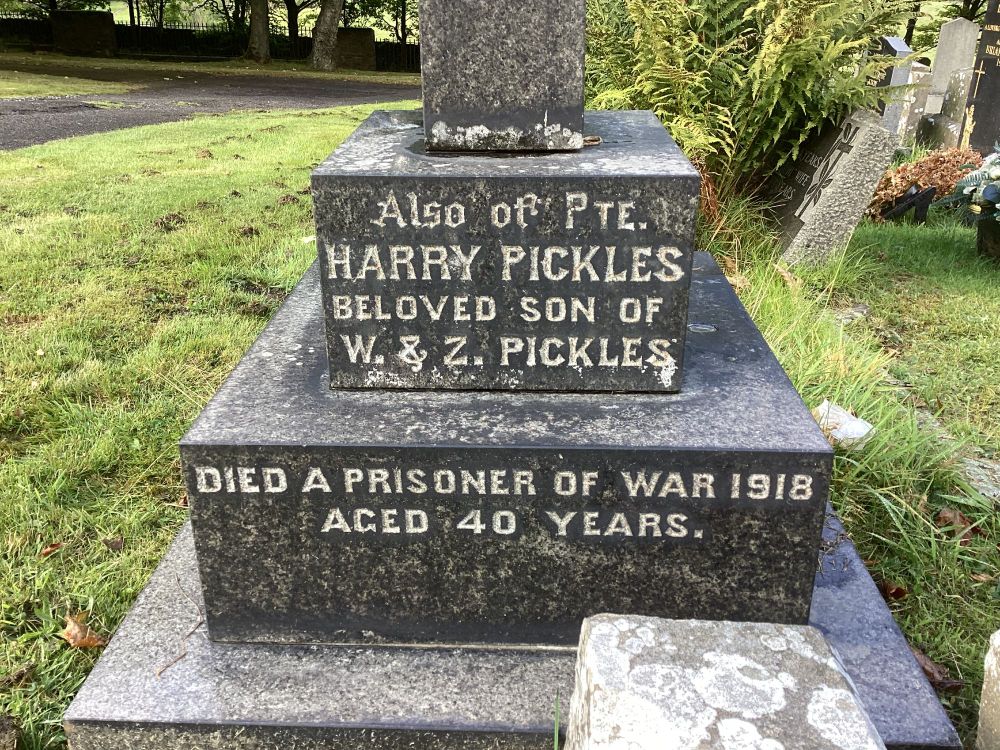 A dark granite stepped gravestone base with an inscription which reads: Also of Pte. Harry Pickles, Beloved son of W & Z Pickles. Died a prisoner of war 1918, Aged 40 years.