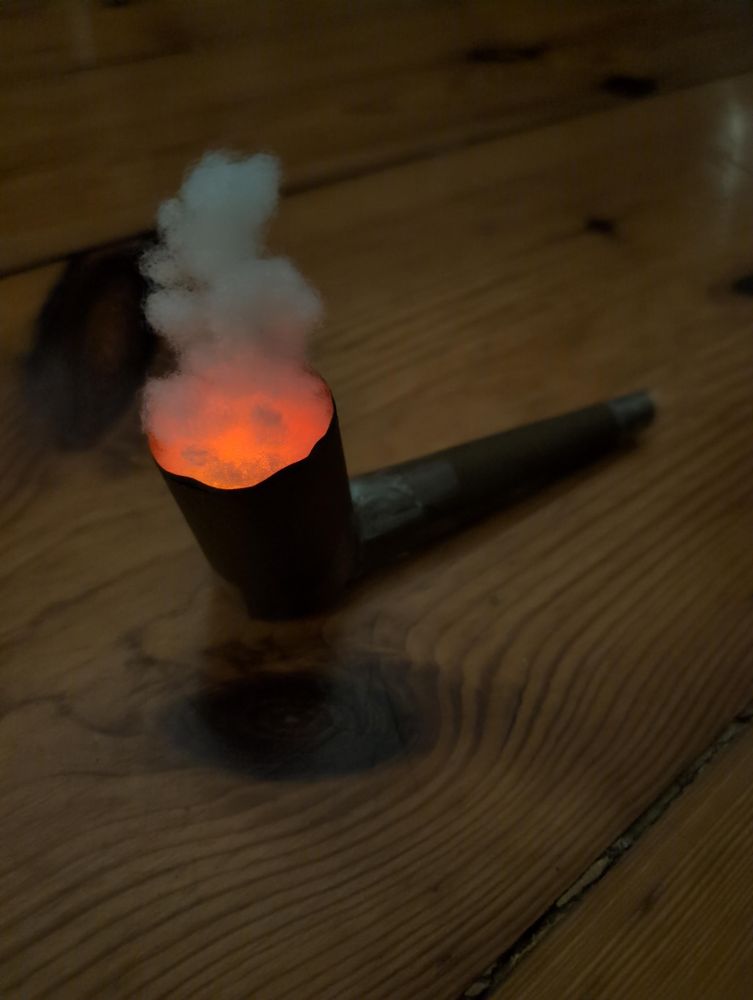 A simple pipe made from a paper cylinder and a paper pipe. Inside the cylinder are two LEDs covered by lose cotton creating the illusion of glow and smoke.