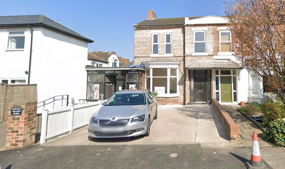 The outside of the house from the listing showing that it has a hairdresser attached, the driveway is concrete not paved and landscaped and the brickwork is a lot messier