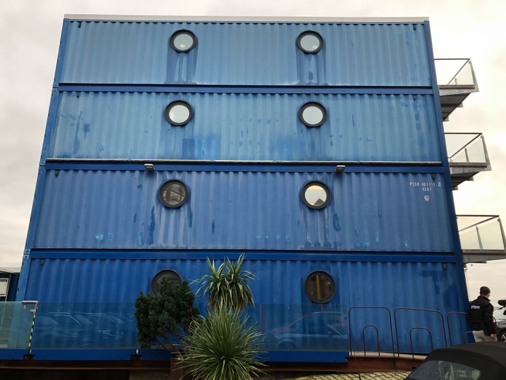 Porthole windows on a building configured from 3 stacked bright blue shipping containers at Trinity Buoy Wharf