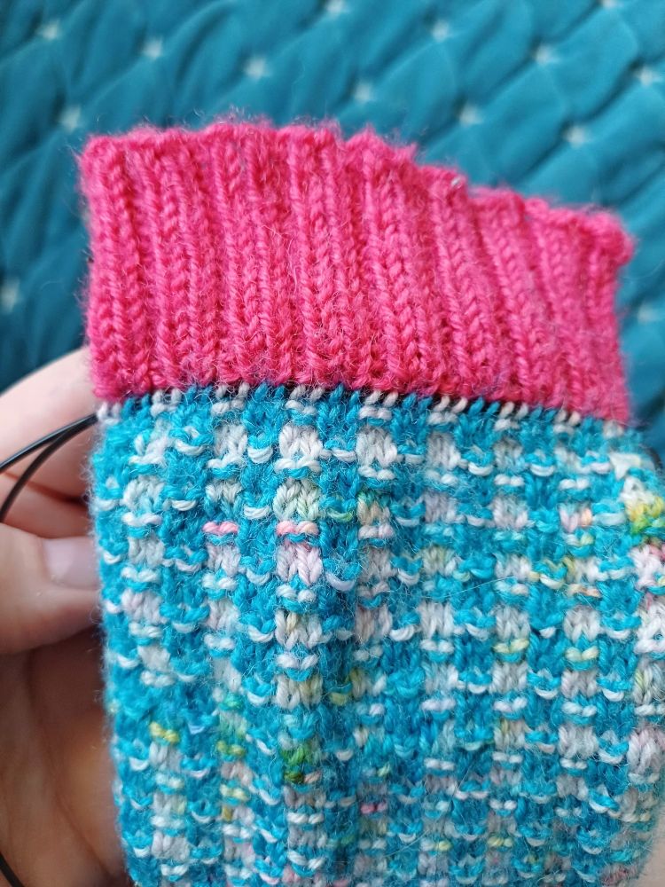 On the blue and white sock with a pink cuff, a cable runs through the row below the cuff. 