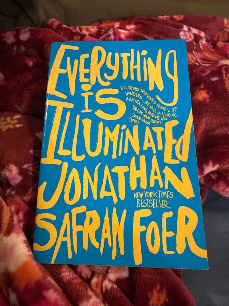 A blue book with yellow font on the cover that reads “Everything is Illuminated” by Jonathan Safran Foer. 
