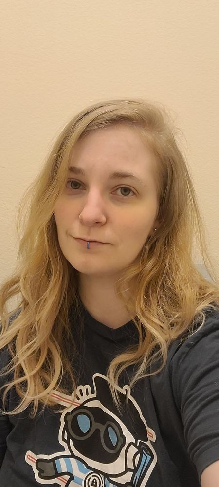 31 y/o white woman with blond hair that is flowing dramatically, without her having done anything to it, as she is about to go to bed. She is smiling, but she is angry about it.