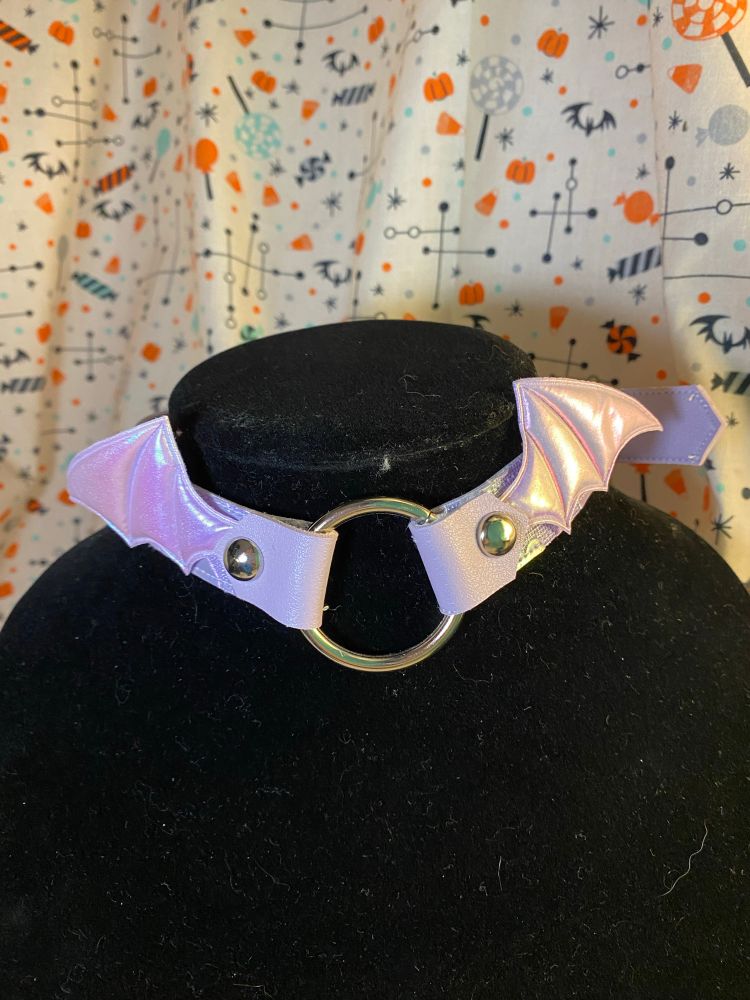 A pearlescent purple choker with bat wings around a ring