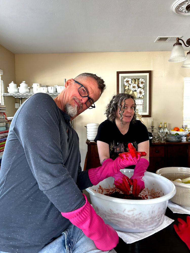 A man posing in pink gloves with the kimchi paste. 