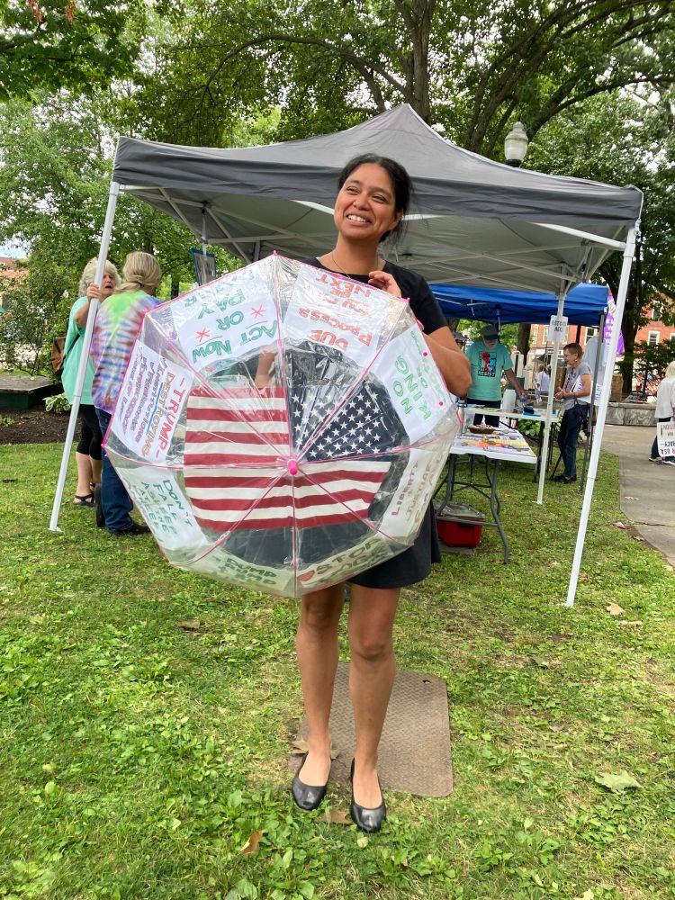 A woman holds an umbrella with protest signs. 