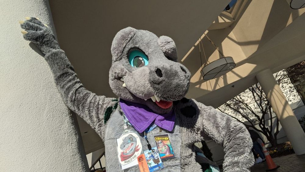 Nullstrukt the dimetrodon fursuit leaning against a column in the front area of the Bewhiskered 2023 hotel