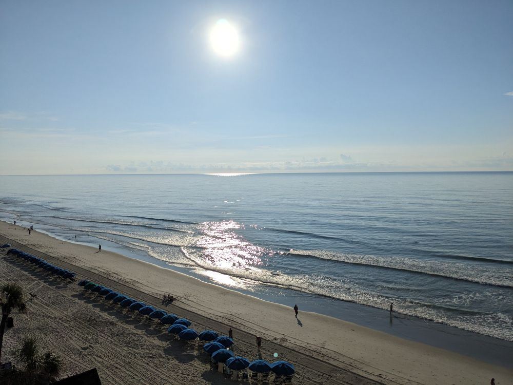 Early morning view of the sun above the beach and ocean taken from a high vantage point.
