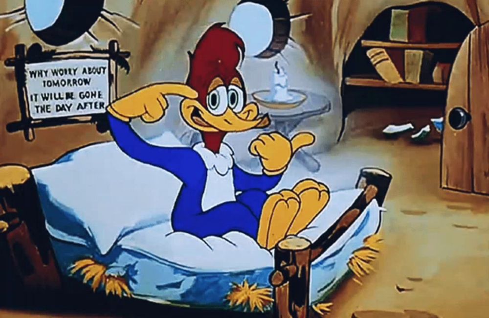 woody woodpecker is sitting on a bed and pointing at a sign