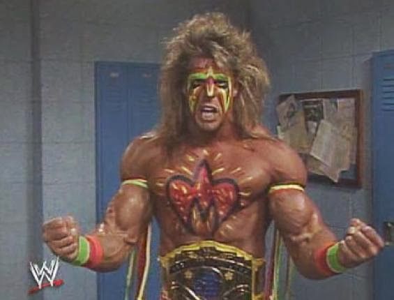 The Ultimate Warrior, wearing his WWF yellow strap Intercontinental Title. His face is painted in bright green, yellow and red. His chest is painted with his symbol which is red and yellow. Straps and armbands of the same green, yellow, and red adorn his arms.