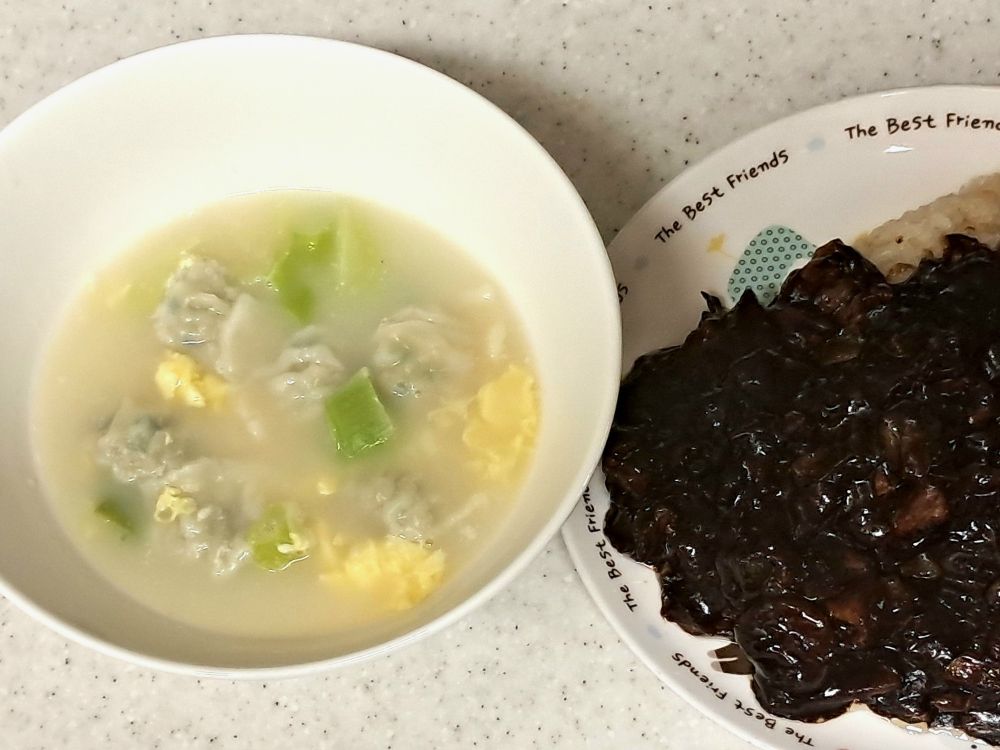 왼 편엔 계란, 파 등을 넣은 만두국, 오른 편엔 짜장을 올린 밥이 있다