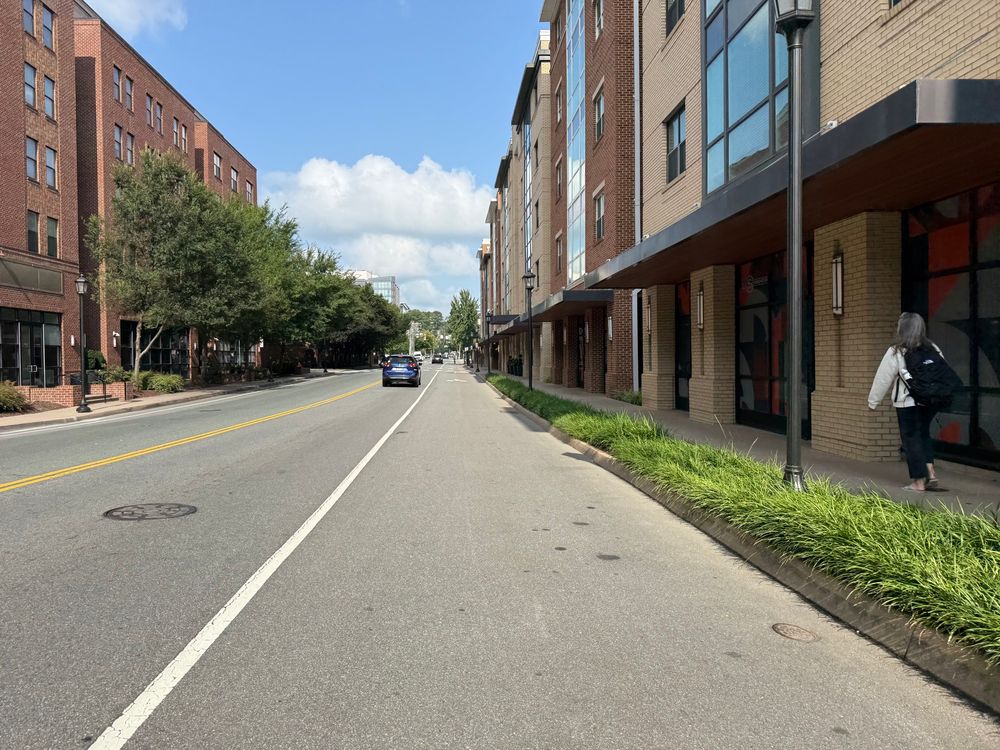 Desolate street exclusively for cars and a wide undefined bike lane and narrow sidewalk. 