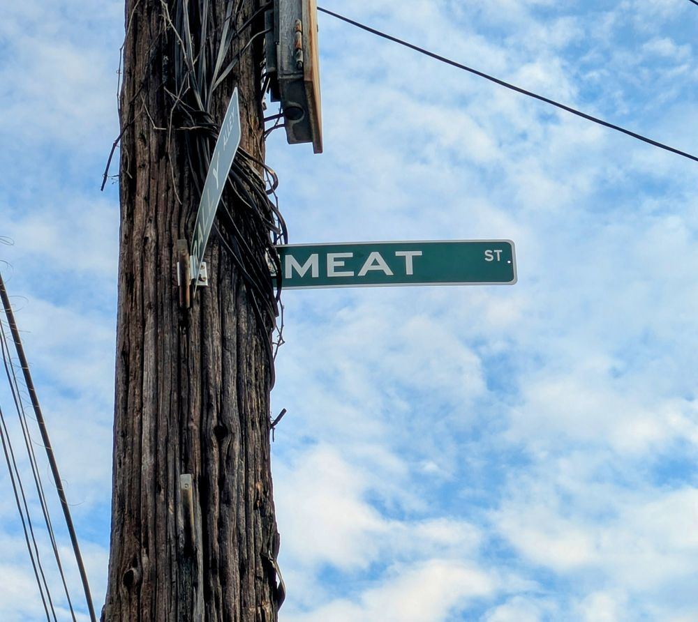 Fake street signs on a telephone pole that say: 