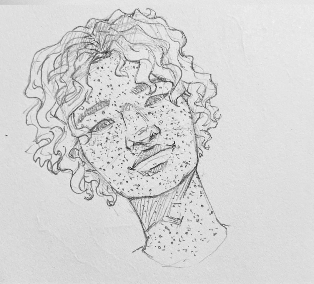 Gabriel, a freckled AMAB Filipino person, with his normal hairstyle of loose waves/curls chin-length with parted bangs. 