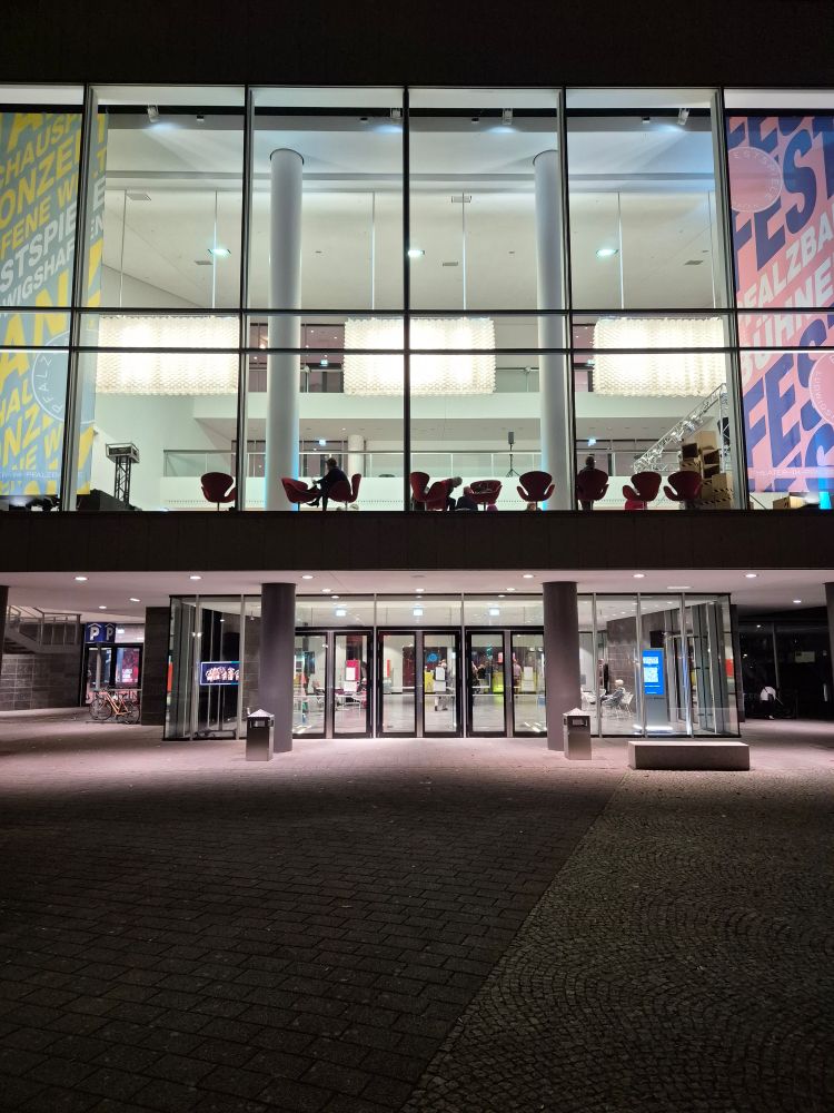Eingang ded Pfalzbau in Ludwigshafen bei Nacht. Das Innere ist beleuchtet.