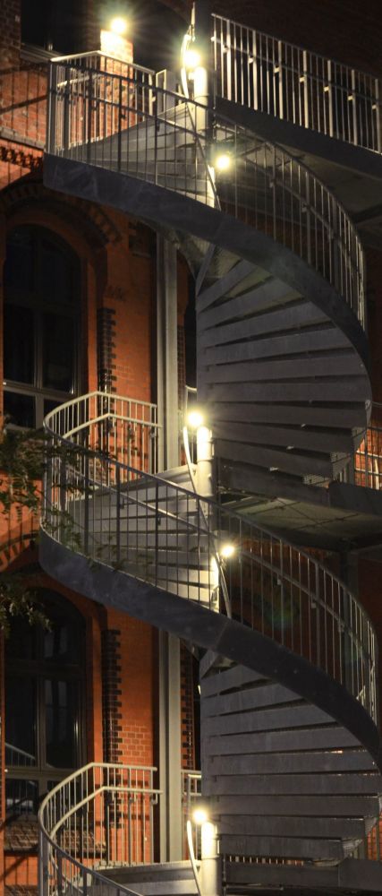 Wendeltreppe aussen an einem Backsteingebäude bei Nacht